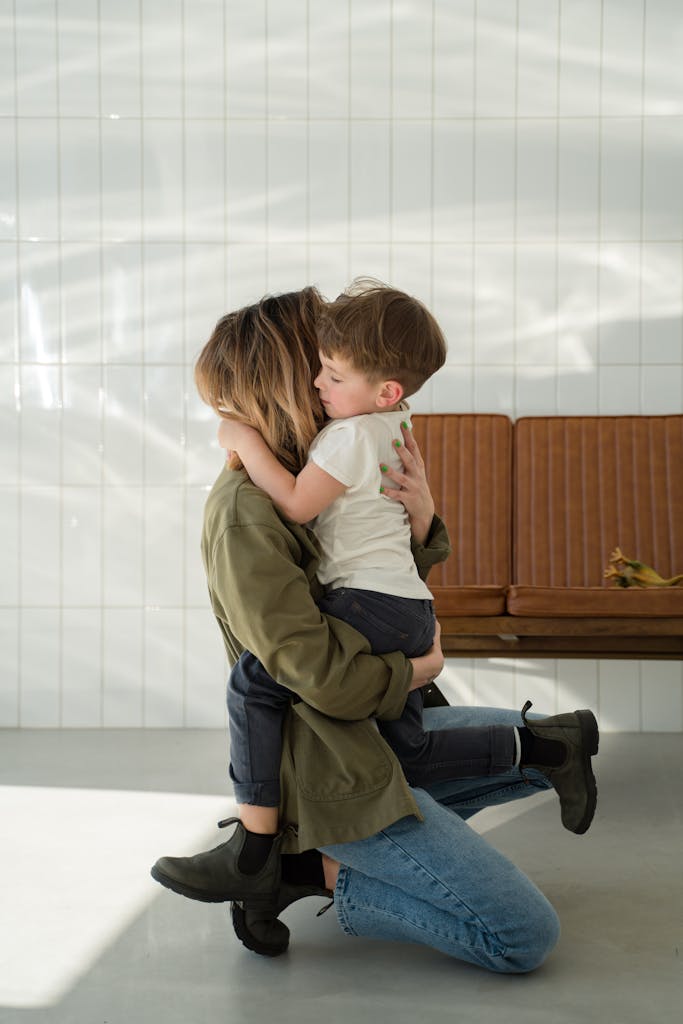 A loving mother embraces her young son in a warm indoor setting, conveying affection and family bonds.