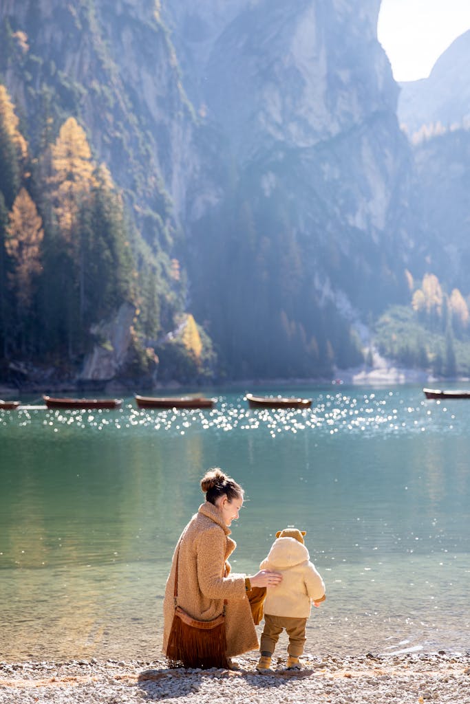 A mother and child enjoying a serene moment by a scenic mountain lake in autumn.